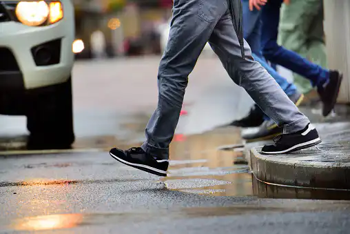 Man stepping over puddle in rain