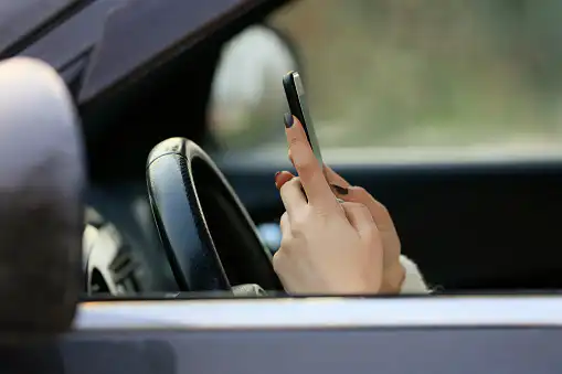 Woman driving car distracted by her mobile phone